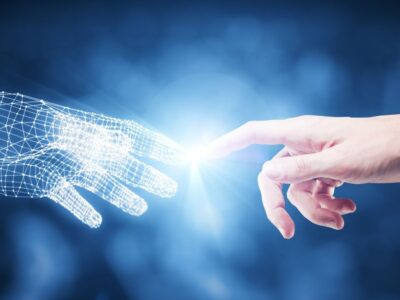Tecnologias do futuro: mão humana e mão de ia se tocando.